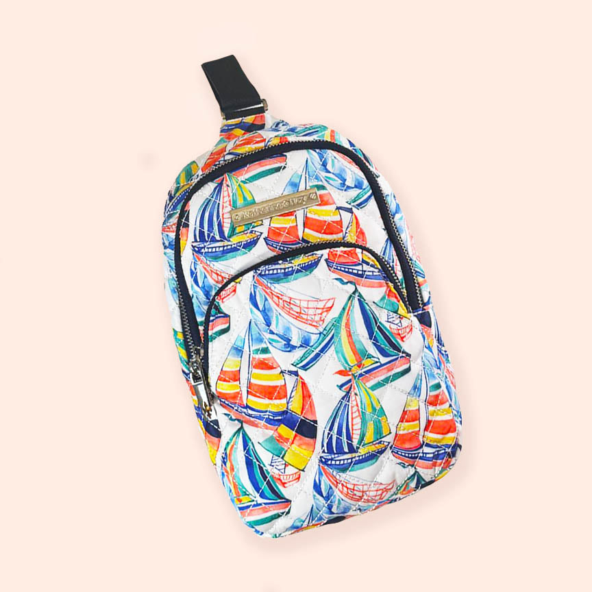 A quilted sling backpack with a colorful sailor-themed pattern, featuring multiple compartments and an adjustable strap.